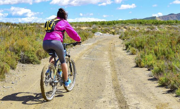 Vrouw rijden een mountainbike door een modderige pad van vuil. - Foto, afbeelding