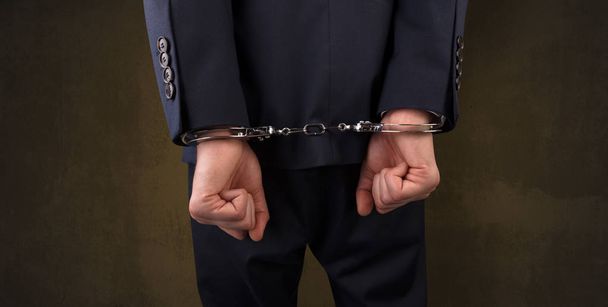 Dark backgrounded close handcuffed man - Foto, Imagen