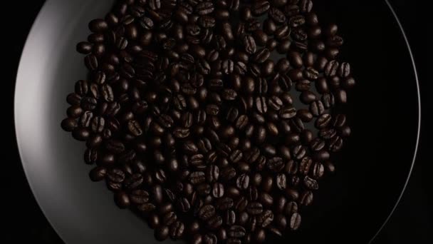 Tiro giratorio de deliciosos granos de café tostados sobre una superficie blanca
 - Imágenes, Vídeo