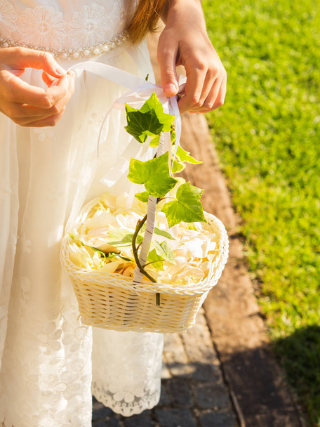 Flor niña en vestido blanco con canasta de pétalos
 - Foto, Imagen