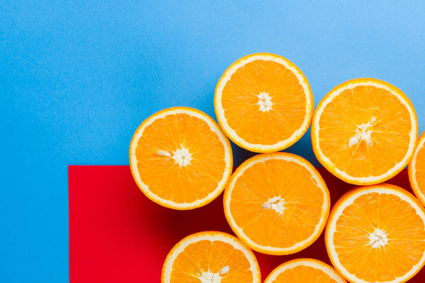 Cut halves of juicy orange on multicolored background. Orange fruit, citrus minimal concept. Creative summer food minimalistic background. Top view, copy space - Zdjęcie, obraz