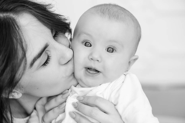 Jonge moeder kus haar baby meisje, close-up. - Foto, afbeelding