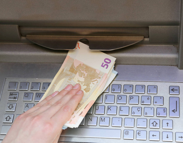 mano que retira billetes de 50 euros de un cajero automático
 - Foto, imagen