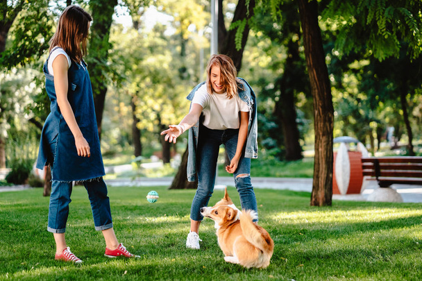 Két női barát játszik a parkban a kiskutyával. - Fotó, kép