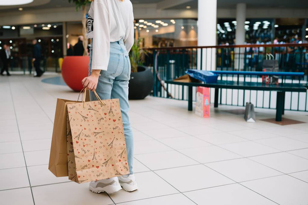 Shopping time, closeup of teenage girl legs with shopping bags at shopping mall - Fotó, kép