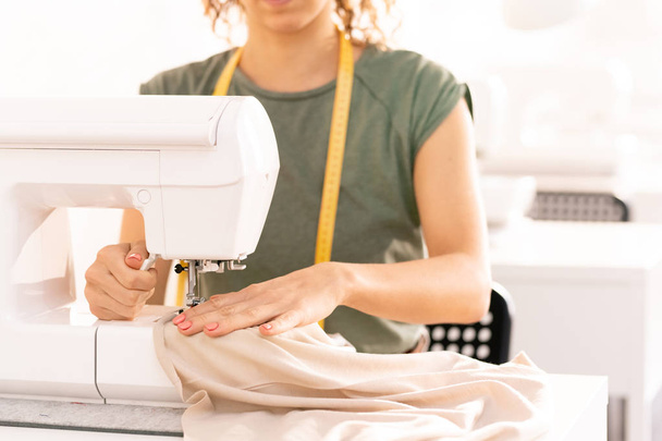 costurera profesional sentado por la máquina de coser mientras se trabaja sobre la nueva colección de temporada en el taller
 - Foto, imagen
