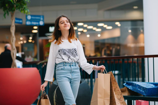 retail, gesture and sale concept - smiling teenage girl with many shopping bags at mall - Foto, imagen