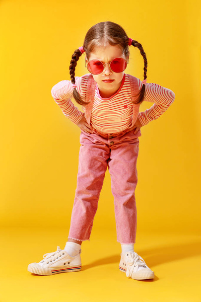 αστείο αστείο παιδί κορίτσι σε ροζ ρούχα σε κίτρινο φόντο    - Φωτογραφία, εικόνα
