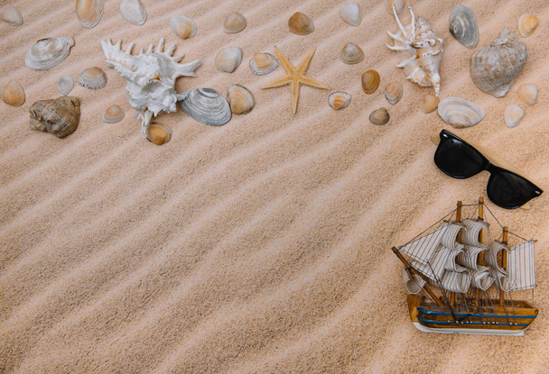 Conchas marinas y velero con arena como fondo. Playa de verano. Vista superior. Fondo con espacio de copia y textura de arena visible
 - Foto, imagen