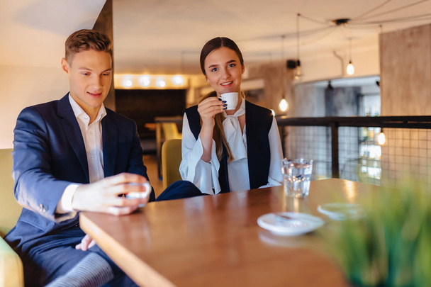 スタイリッシュなカップルがカフェ、若手ビジネスマン、フリーランサーで朝コーヒーを飲む - 写真・画像