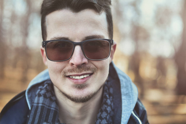 Fashion portrait of european guy in sunglasses walking on park - Photo, Image