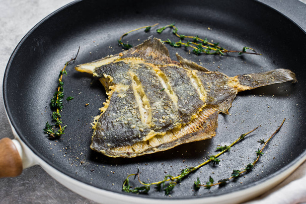 Fried flounder in a pan. Gray background, top view. - Photo, Image