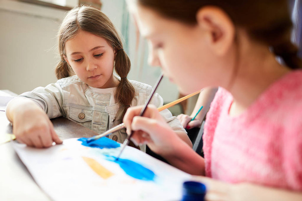 Primer plano de dos niñas pintando juntos en clase de arte o en casa, espacio para copiar
 - Foto, imagen