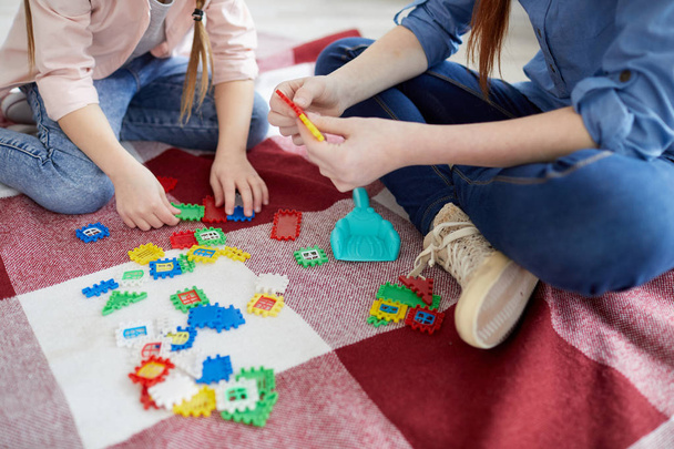 Close up portrait of two sisters playing with puzzles sitting on floor, copy space - 写真・画像