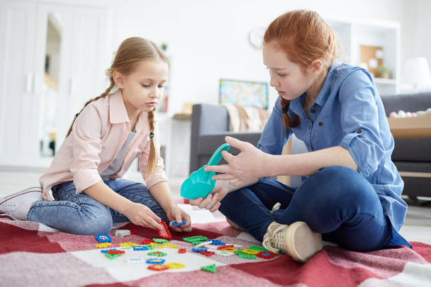 Full length portrait of two sisters playing with puzzles sitting on floor, copy space - Fotoğraf, Görsel