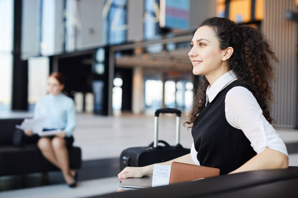 Seitenansicht Porträt einer lächelnden jungen Frau, die in der Flughafenlobby aufgeregt auf das Reisen wartet, Kopierraum - Foto, Bild