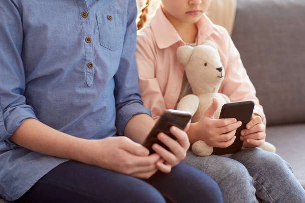 Closeup of two children using smartphones at home texting and scrolling through social networks, copy space - Foto, afbeelding