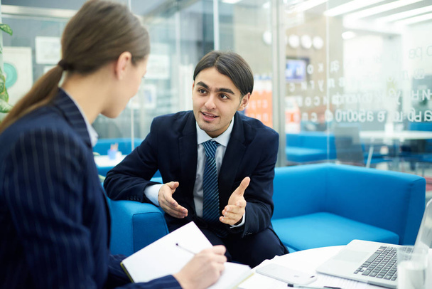 Portrait of smiling young businessman talking to female colleague during work meeting in office, copy space - Foto, afbeelding