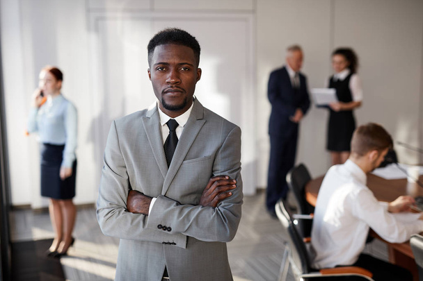 Taille up portret van Afro-Amerikaanse zakenman staande met armen gekruist in conferentieruimte, kopieer ruimte - Foto, afbeelding