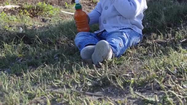 Bonito menino de dois anos de idade bebendo água de garrafa na natureza
 - Filmagem, Vídeo