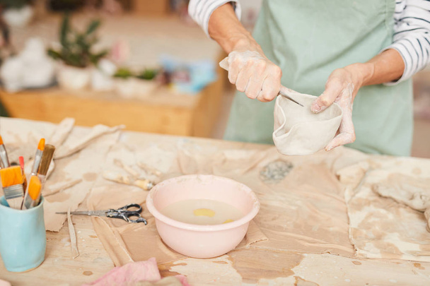 Closeup portrait of unrecognizable female artist shaping clay while working in pottery workshop, copy space - Photo, Image