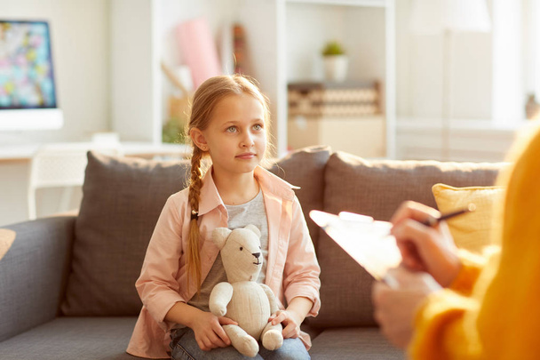 Porträt eines süßen kleinen Mädchens, das während einer Therapiesitzung zu Jugendfragen Psychologen zuhört, Kopierraum - Foto, Bild