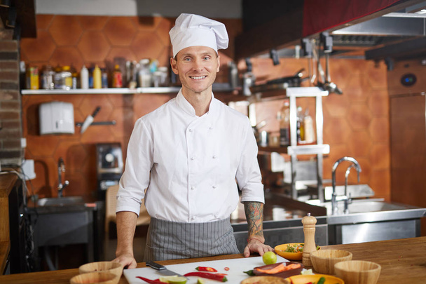 Waist up portrait of handsome chef posing in kitchen and smiling at camera, copy space - Zdjęcie, obraz