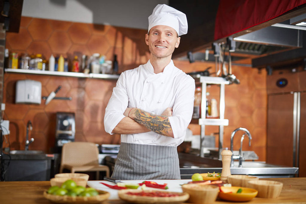 Waist up portrait of handsome chef posing in kitchen standing with arms crossed, copy space - Photo, Image
