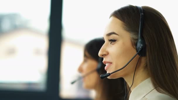 4K. Trabajo en el centro de llamadas. Dos mujeres jóvenes operadoras responden cliente
  - Metraje, vídeo