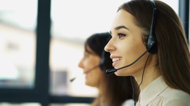 4K. Trabajo en el centro de llamadas. Dos jóvenes mujeres bonitas operadores responden cliente
  - Metraje, vídeo