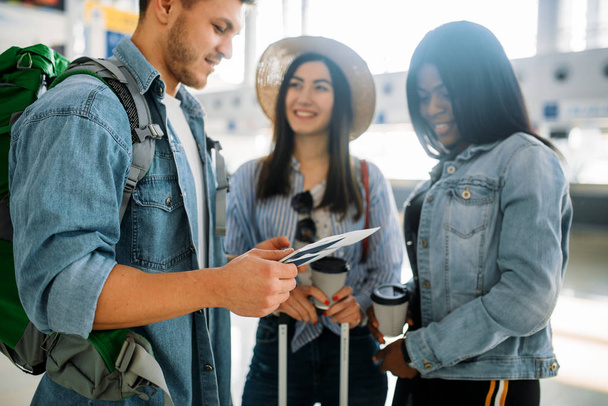 Drei Touristen mit Gepäck warten am Flughafen auf ihre Abreise. Passagiere mit Gepäck im Flugterminal, glückliche Reise - Foto, Bild