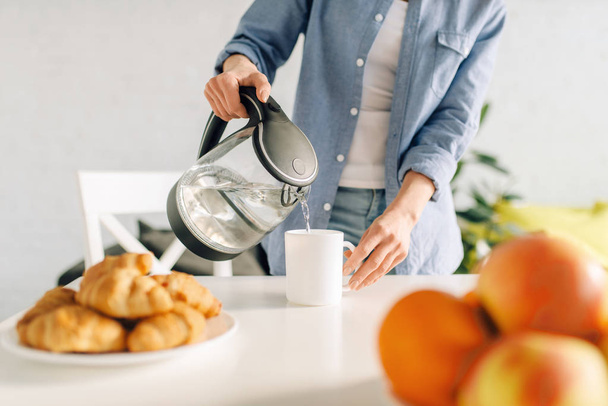 Šťastná žena vaří snídani v kuchyni. Žena, která je doma ráno, zdravá výživa a životní styl - Fotografie, Obrázek