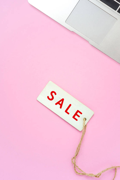 Sale tag and laptop on pink background, online shopping - Fotografie, Obrázek