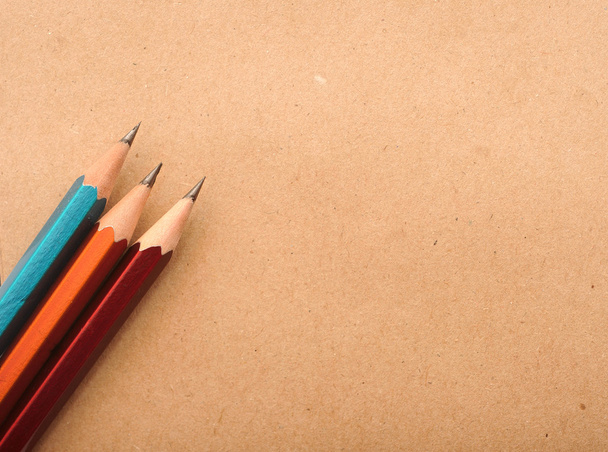 барвисті олівці на коричневому паперовому фоні, картонна нота
 - Фото, зображення