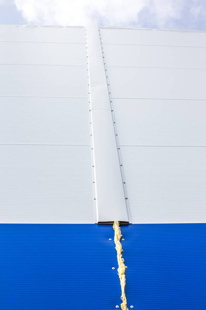 The texture of the wall of the building, made of white and blue sandwich panels. Visible structure of the seam between the panels. - Φωτογραφία, εικόνα