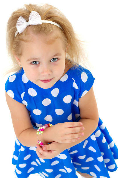 A little girl puts a bracelet on her arm. - Foto, imagen