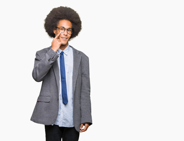 Young african american business man with afro hair wearing glasses Pointing to the eye watching you gesture, suspicious expression - Foto, Imagem