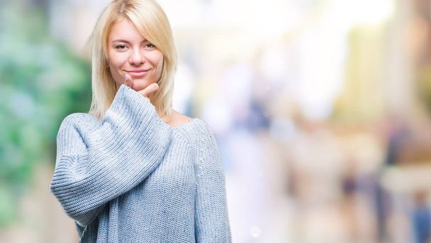 Young beautiful blonde woman wearing winter sweater over isolated background looking confident at the camera with smile with crossed arms and hand raised on chin. Thinking positive. - Fotó, kép
