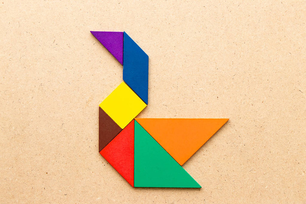 Puzzle couleur tangram en forme de cygne sur fond bois
 - Photo, image
