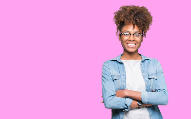 Belle jeune femme afro-américaine portant des lunettes sur fond isolé heureux visage souriant avec les bras croisés regardant la caméra. Personne positive
. - Photo, image
