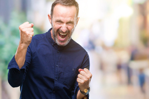 Middle age hoary senior man over isolated background very happy and excited doing winner gesture with arms raised, smiling and screaming for success. Celebration concept. - Photo, Image