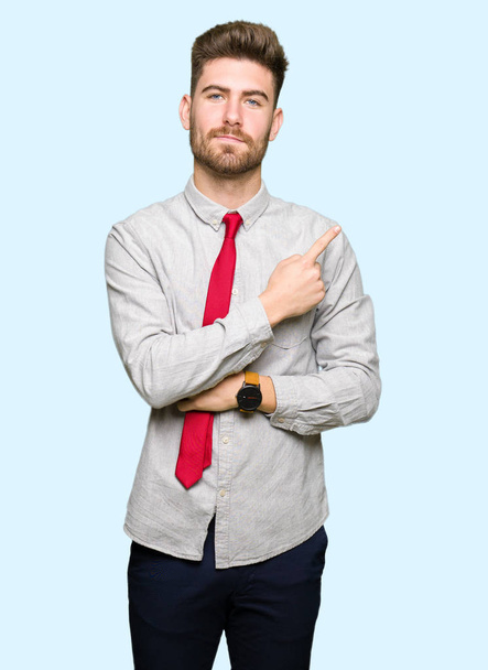 Mladý pohledný obchodní muž ukázání prstem ruky na straně zobrazuje reklamu, vážný a klidný obličej - Fotografie, Obrázek
