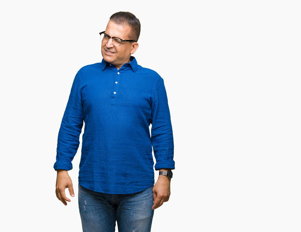Middle age arab man wearing glasses over isolated background winking looking at the camera with sexy expression, cheerful and happy face. - Zdjęcie, obraz
