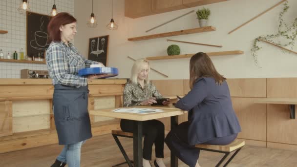 Cafe waitress serving coffee to women using tablets - Video, Çekim