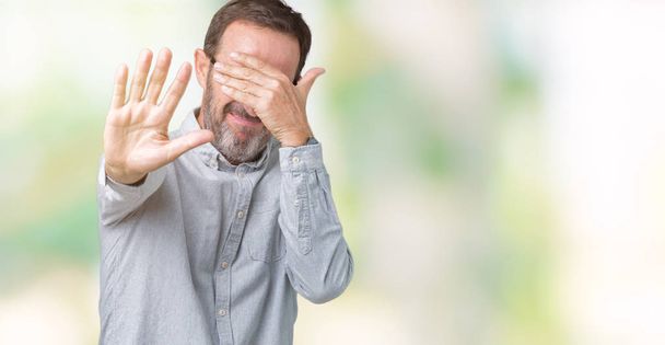 Handsome middle age elegant senior man wearing glasses over isolated background covering eyes with hands and doing stop gesture with sad and fear expression. Embarrassed and negative concept. - Fotoğraf, Görsel