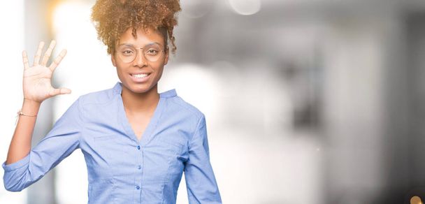 Γυναίκα όμορφη νεαρή αφρικανική αμερικανική επιχείρηση πέρα από το απομονωμένο υπόβαθρο δείχνει και δείχνει προς τα επάνω με τα δάχτυλα αριθμός πέντε ενώ χαμογελώντας αυτοπεποίθηση και χαρούμενοι. - Φωτογραφία, εικόνα