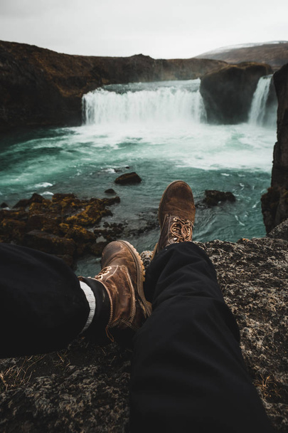 Hiker boots on rocks of cliff over waterfall in beautiful landscape in Iceland, Europe - Foto, Imagem