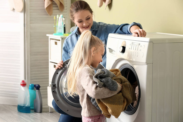 若い女性と彼女の小さな娘が自宅で洗濯をします - 写真・画像
