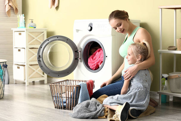 Giovane donna e la sua piccola figlia facendo il bucato a casa
 - Foto, immagini