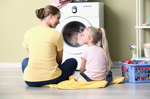 Jeune femme et sa petite fille faisant la lessive à la maison
 - Photo, image